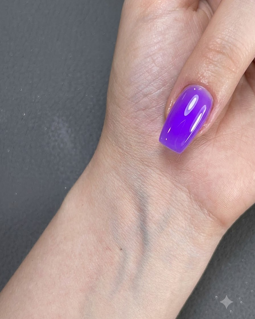 Una mano con ununghia smaltata di viola appoggiata vicino a una superficie sotto lilluminazione.