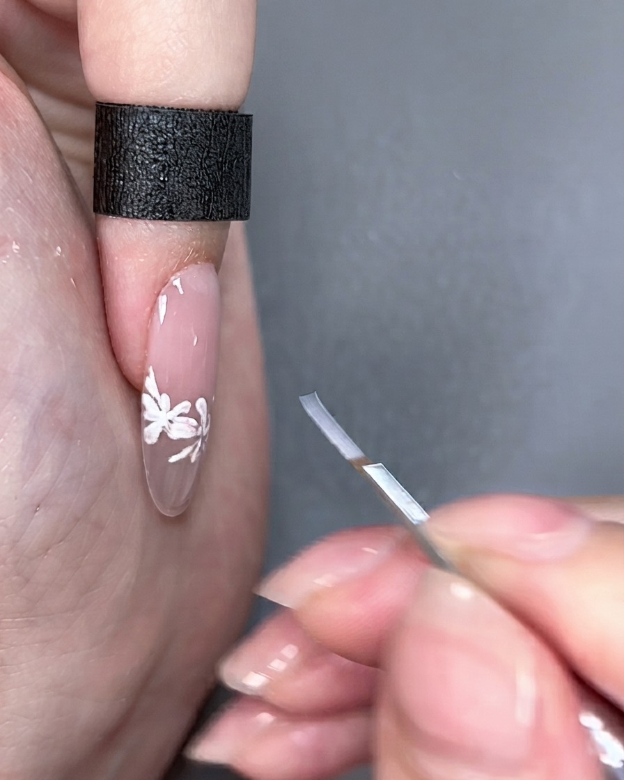Un pennello per nail art tenuto accanto a ununghia finita sotto le luci dello studio.