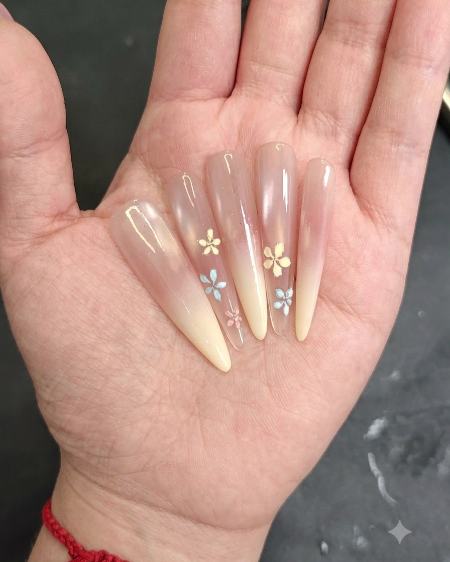 Primo piano di una mano che applica gel blush rosa sulla punta di ununghia a mandorla.