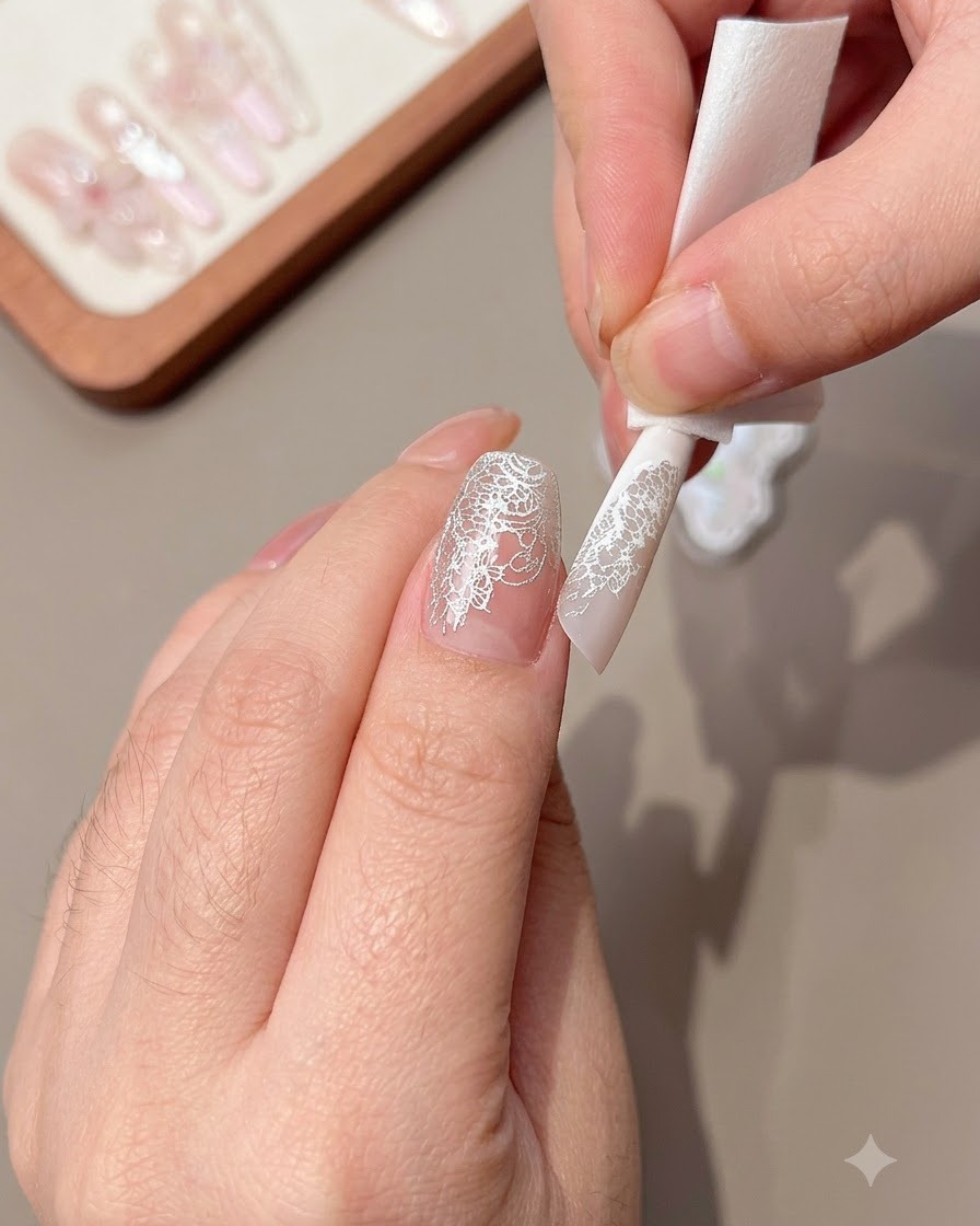 Un primo piano di una mano che pulisce il pizzo in eccesso dal bordo di ununghia decorata.