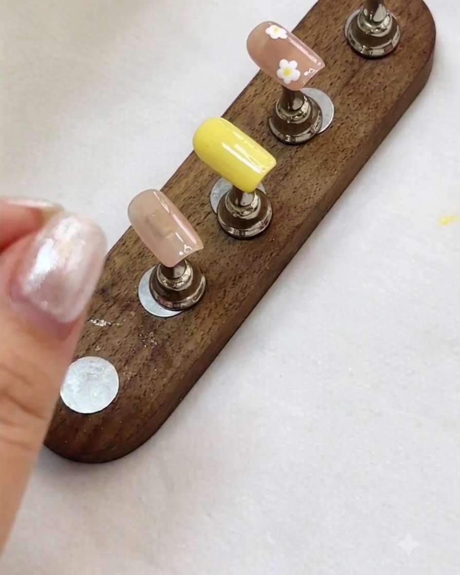 Un supporto per esposizione per unghie che mostra design di nail art floreali e nudi finiti pronti per il passaggio successivo.