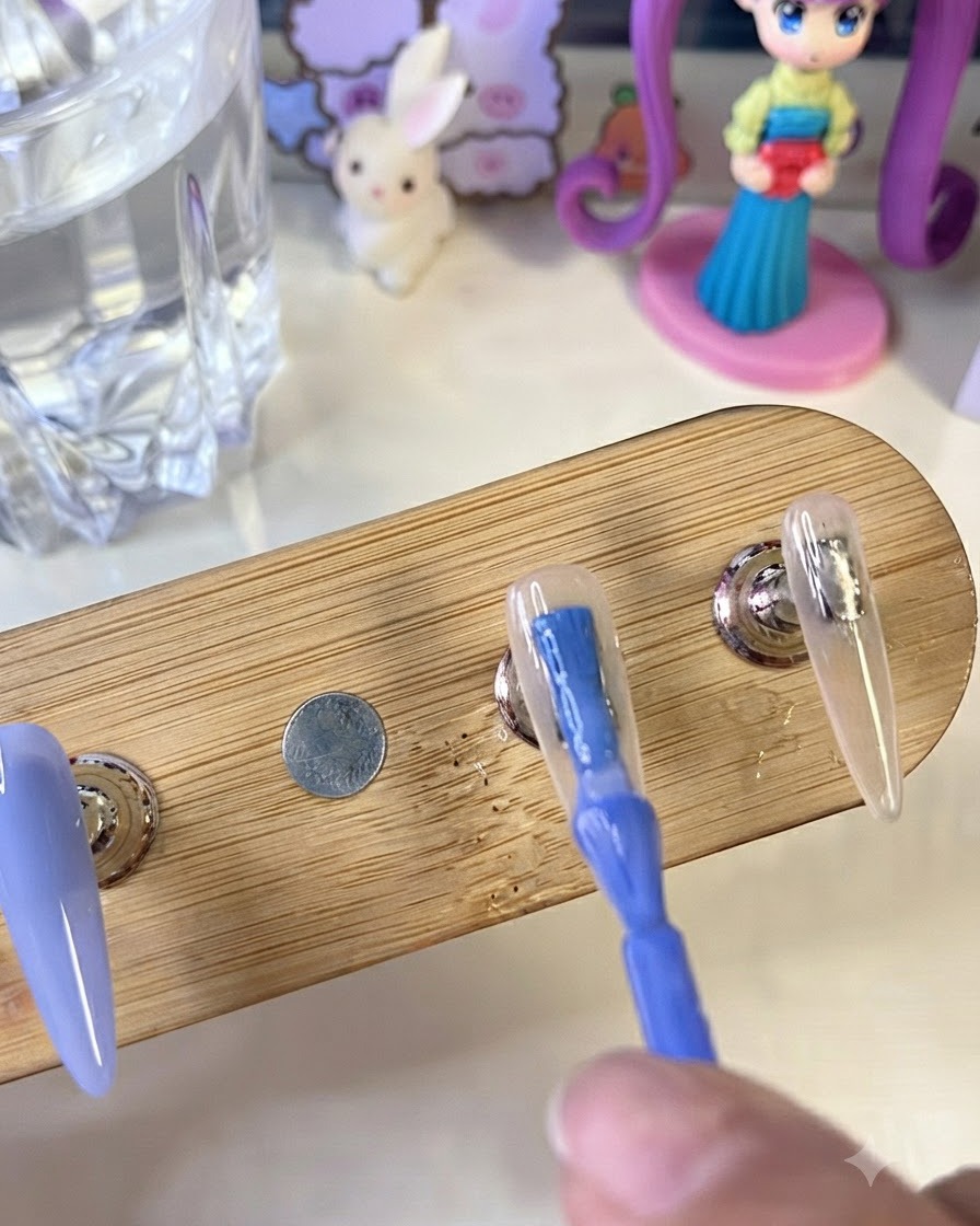 Un pennello che applica uno smalto gel blu brillante su una tip artificiale su un supporto di legno, accanto a ununghia dipinta con una base bianco latte.