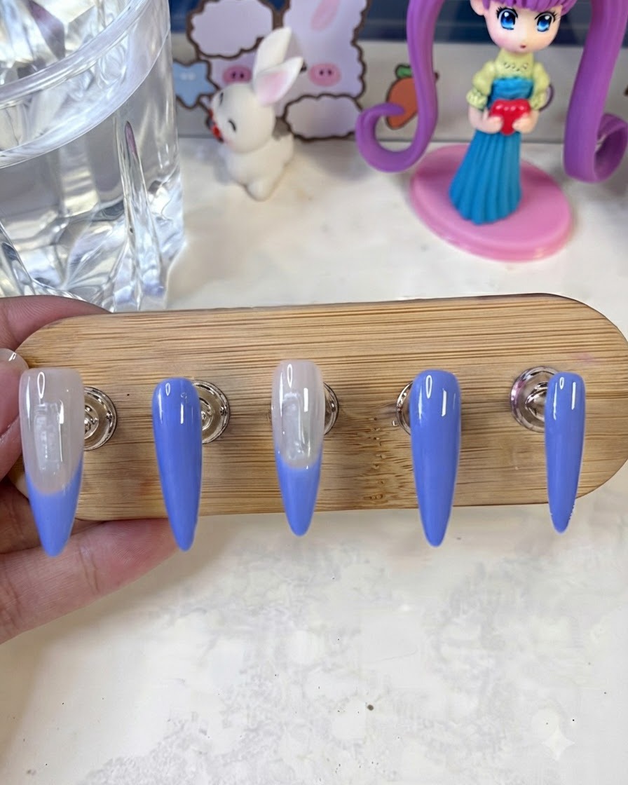 Pennello da nail art che applica un secondo strato di colore French blu sui bordi dellunghia su un supporto da esposizione.