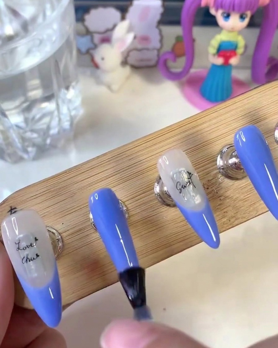 Un pennello che applica uniformemente il top coat opaco sulla superficie delle unghie dipinte su un supporto di legno.