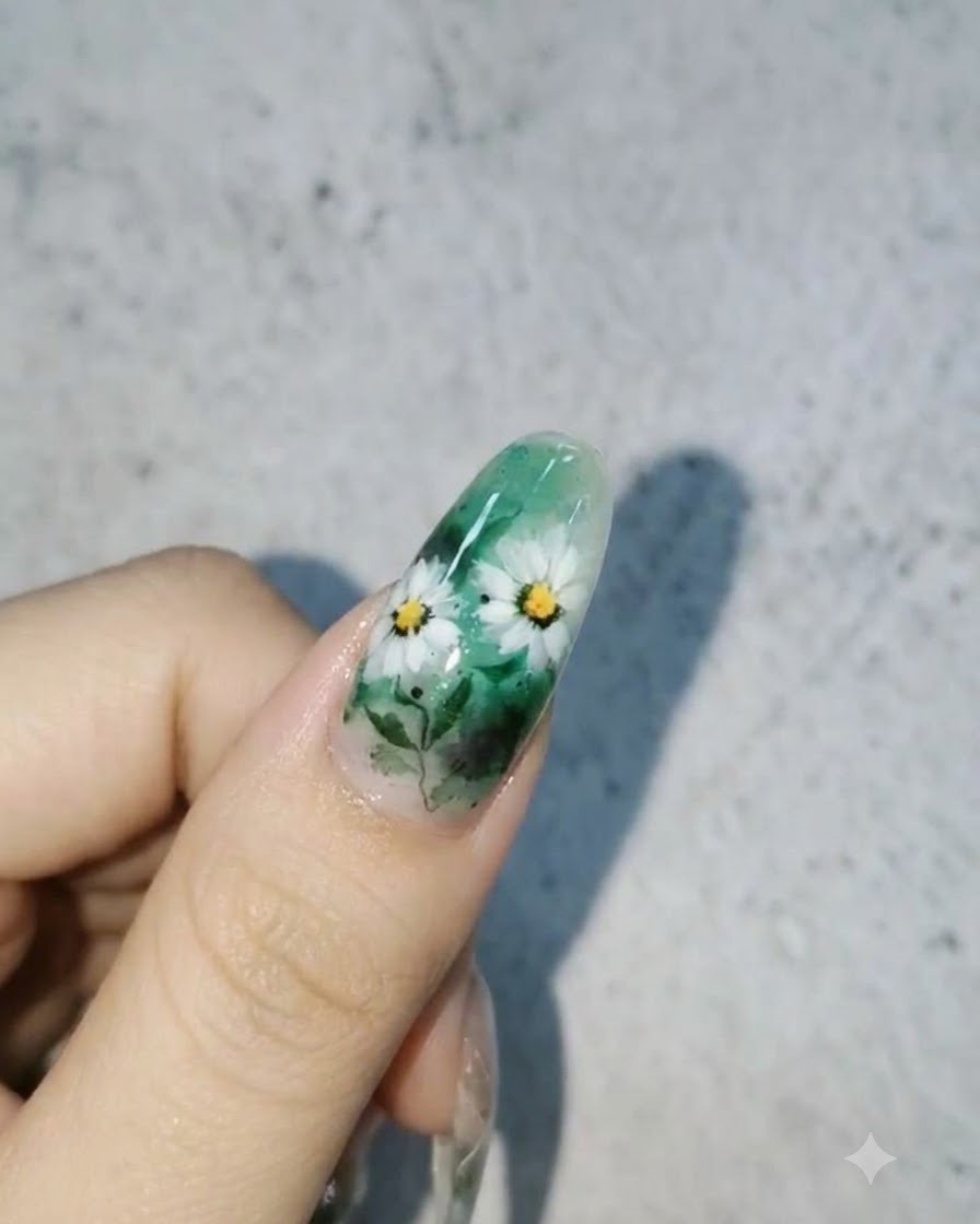 Un design per unghie finito con margherite bianche e foglie su uno sfondo verde con gocce dacqua 3D lucide sulla superficie.