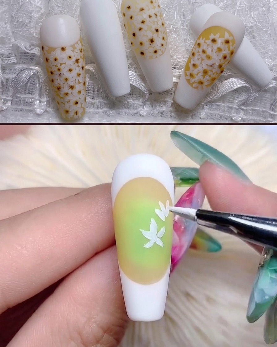 Un pennello sottile dipinge forme di petali di margherita bianchi sullunghia dai toni gialli.