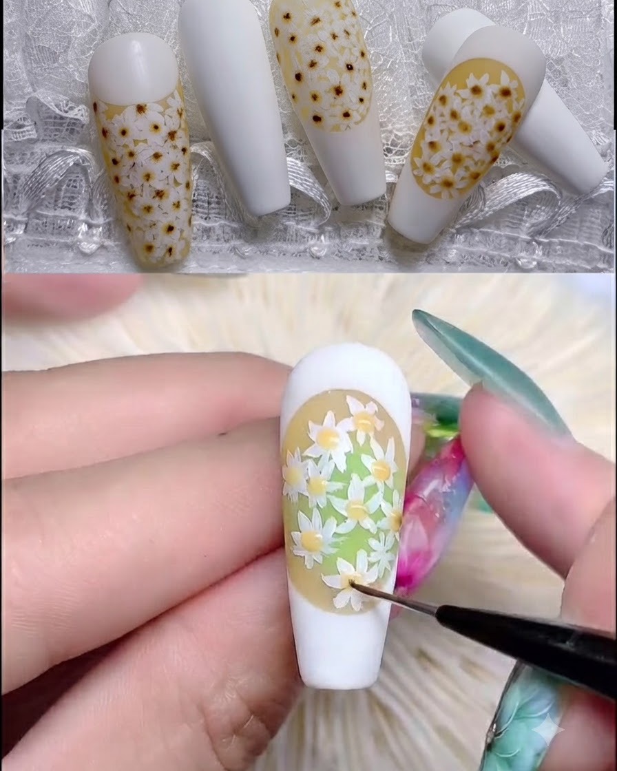 Un pennello per unghie applica il rubber top coat trasparente su un design texturizzato di margherite.
