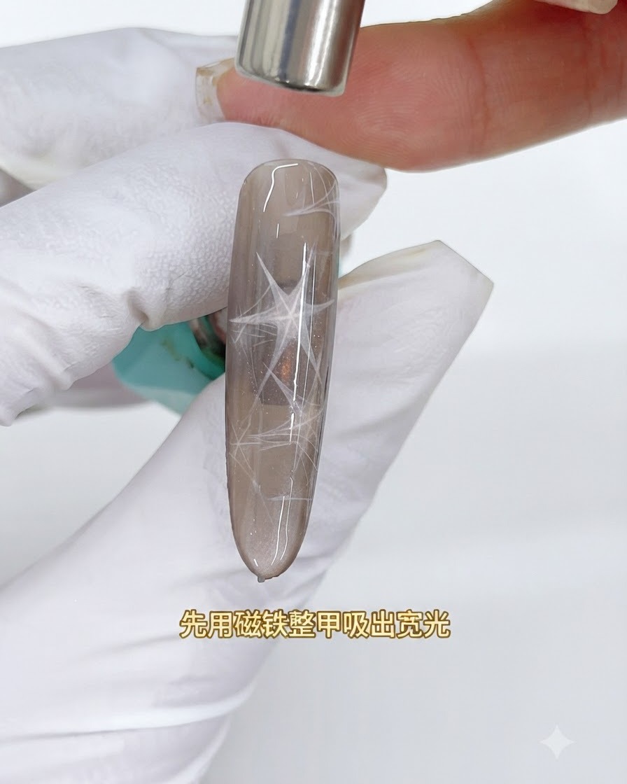 Un magnete cilindrico posizionato sopra ununghia cat eye marrone per estrarre unampia fascia di luce riflettente.