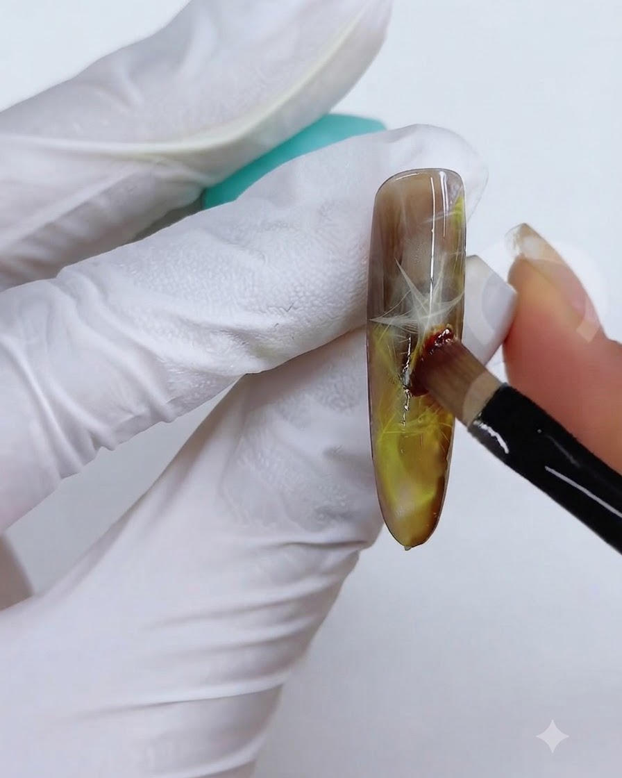 Una tecnica con pennello e spugna utilizzata per sfumare il colore giallo-marrone sulla superficie dellunghia.