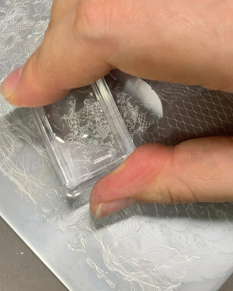 Un timbro trasparente che trasferisce un motivo in pizzo bianco su una tip trasparente.