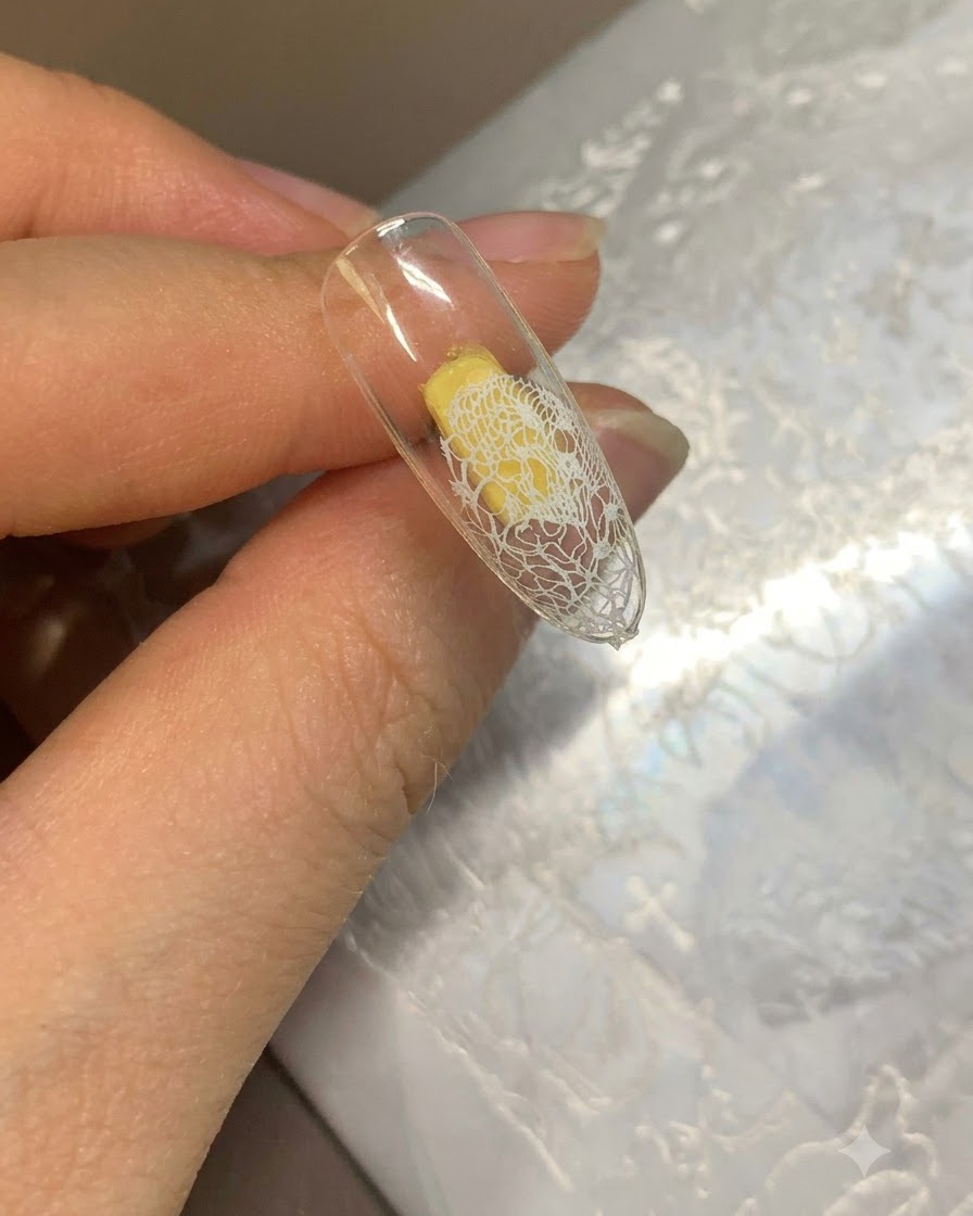 Una tip trasparente con pizzo bianco trasferito sulla punta e base in gel beige applicata sul resto.