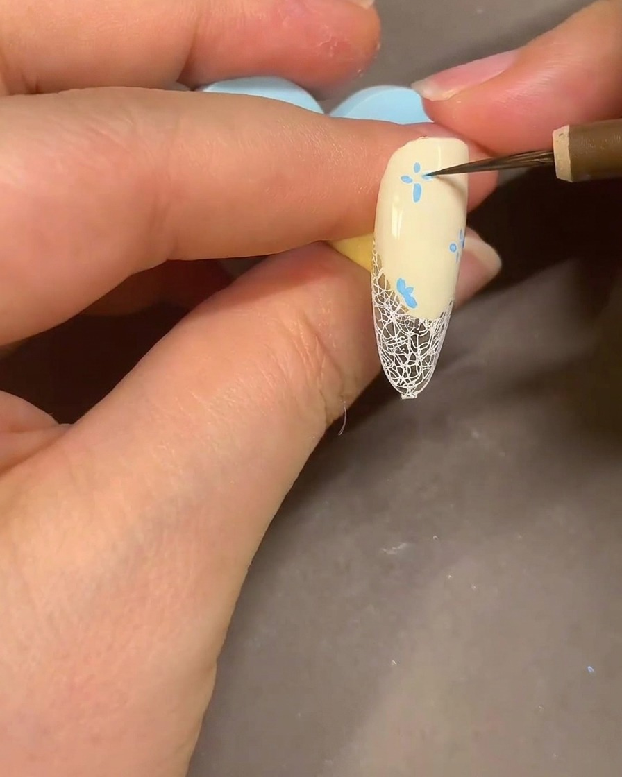 Un pennello da acquerello che sfuma i petali di un fiore blu con lalcol per un effetto fumé.
