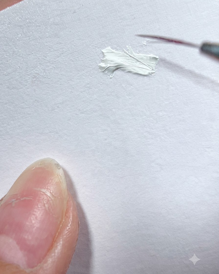 Un pennello liner fine che preleva gel colore bianco da una tavolozza.
