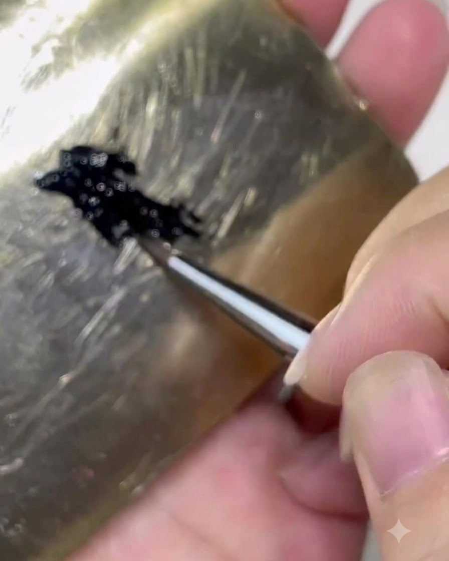 Un pennello che preleva il gel nero da una tavolozza su circa un terzo del corpo del pennello.