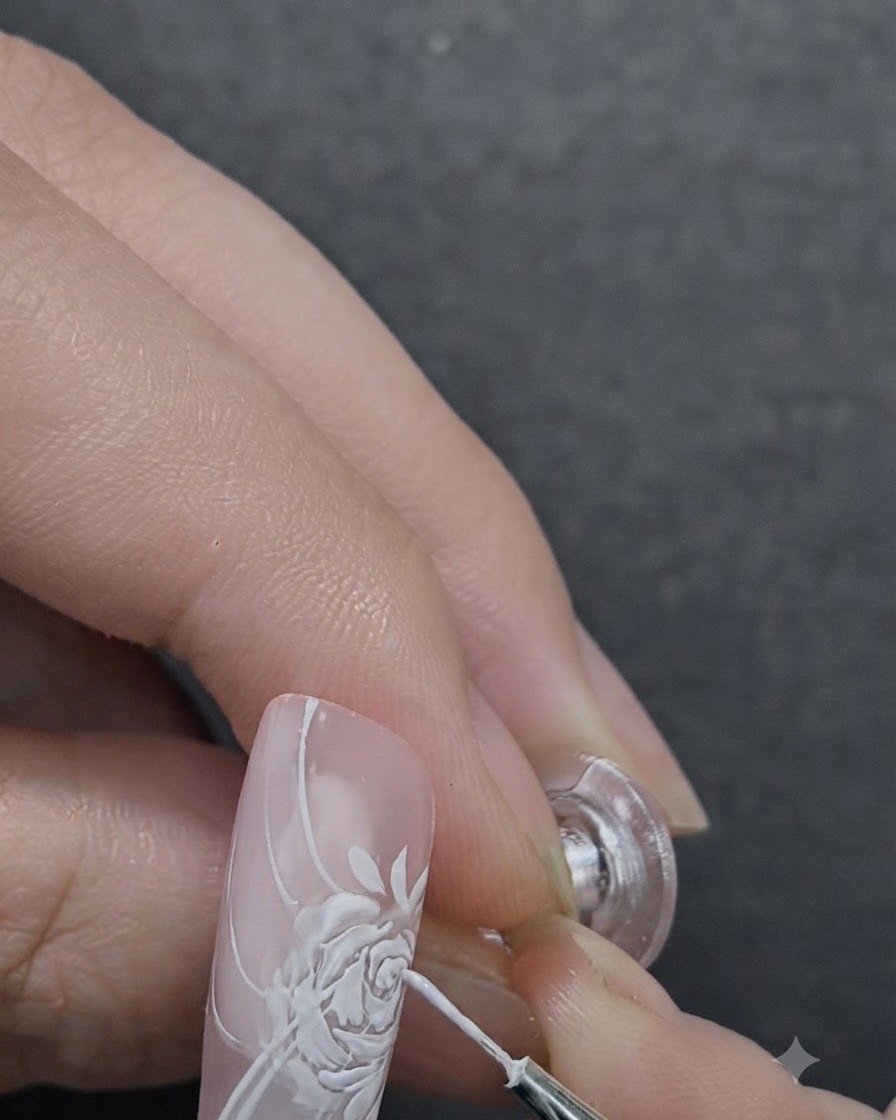 Unartista delle unghie che applica il gel scultoreo 3D al centro di una rosa dipinta usando un pennello di dettaglio.