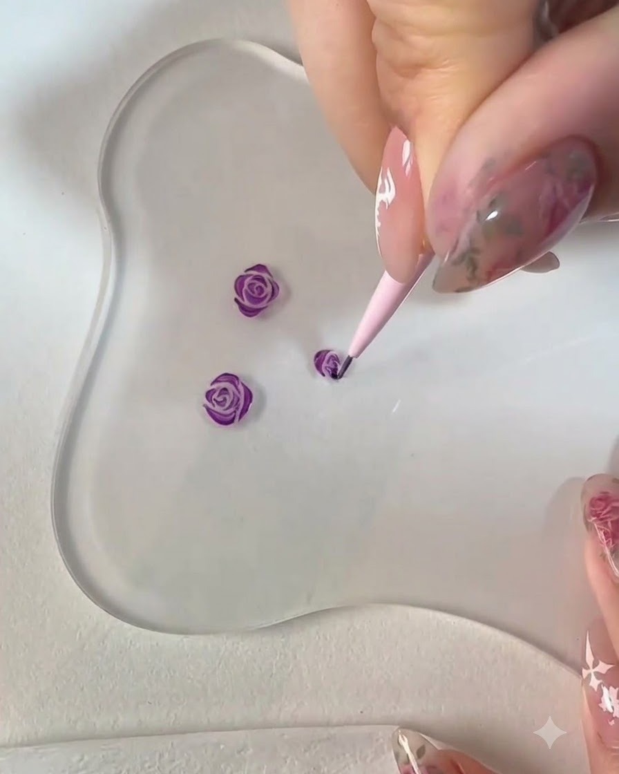 Un pennello liner fine che dipinge ulteriori petali lungo il contorno inferiore della nail art con rosa viola.