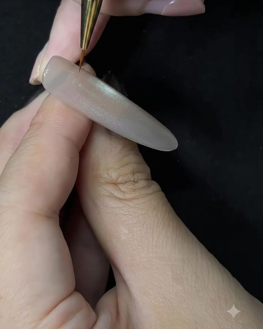 Primo piano di unonicotecnica che utilizza un pennello di precisione fine per applicare il gel bianco con un movimento di tamponamento su unextension per unghie scolpita.