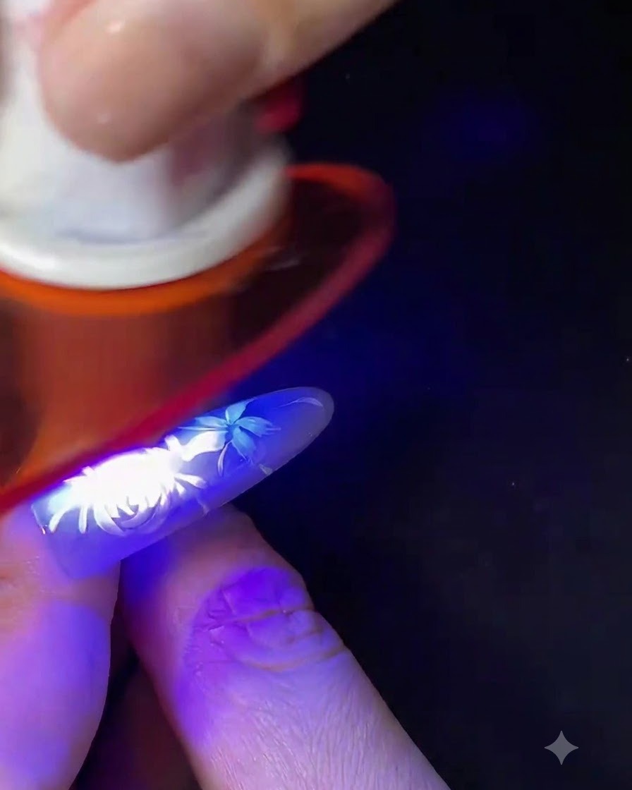 Un dito con nail art floreale bianca completata in fase di polimerizzazione sotto una piccola lampada per unghie blu UV/LED.