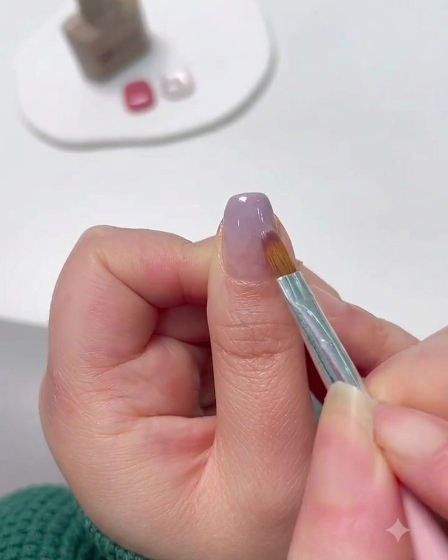 Un pennello da nail art di precisione sfuma il gel lavanda dalla punta verso lalto per creare un ombré.