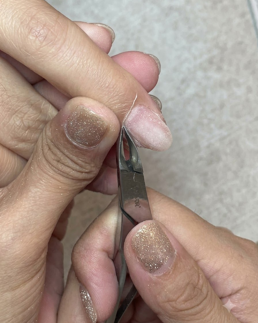 Tronchesine per cuticole in metallo affilate che tagliano accuratamente una striscia di pelle morta dalla linea delle cuticole.