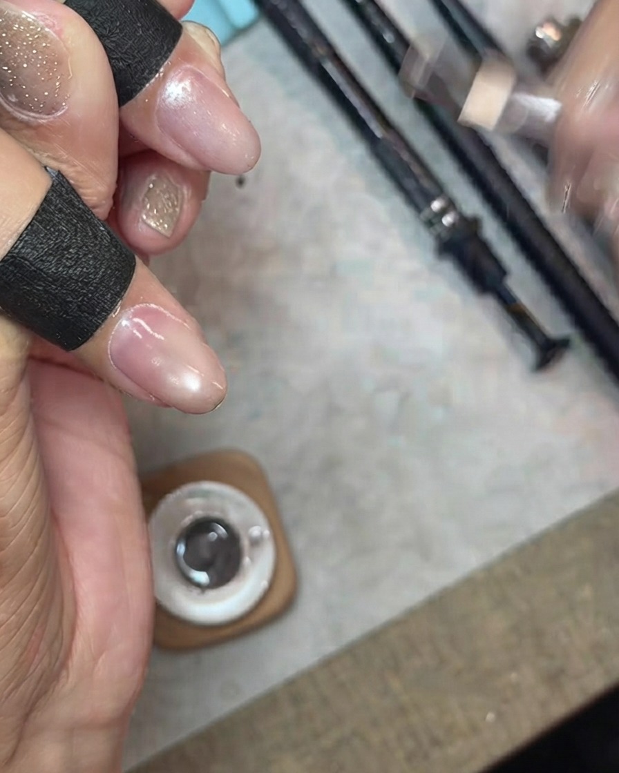 Applicazione di uno strato di gel cat-eye trasparente e finemente brillante su ununghia.