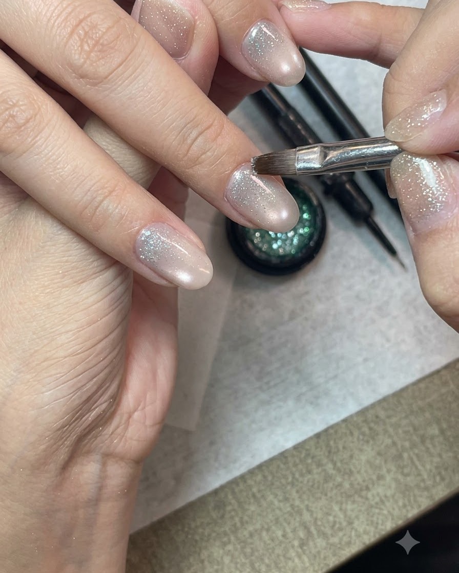 Un pennello dettagliato per nail art che applica il gel glitter crushed diamond sulla metà inferiore di ununghia preparata.