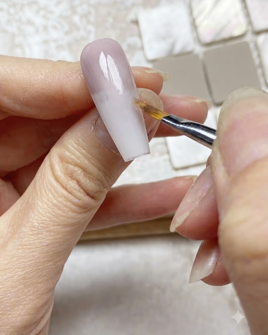 Un pennello ombré sfuma delicatamente il bordo di uno strato di gel viola verso il basso su unestensione ungueale nude.