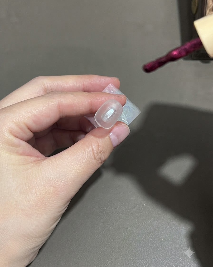 Un pennello che applica lo smalto semipermanente cat-eye viola scuro su ununghia.