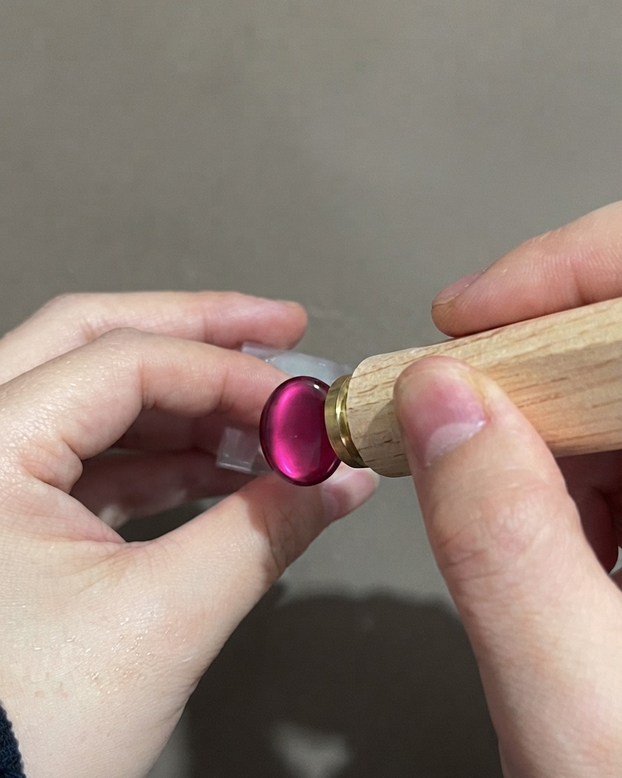 Una mano che tiene uno strumento stampino vicino a ununghia cat-eye sfumata viola finita.