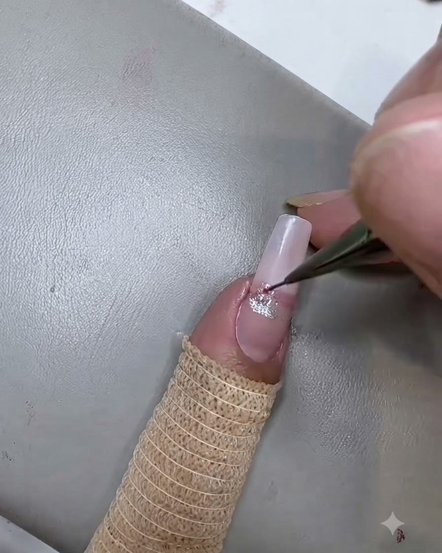Un pennello liner sottile che applica una seconda striscia di gel cat eye rosa sotto la striscia argentata sullunghia.