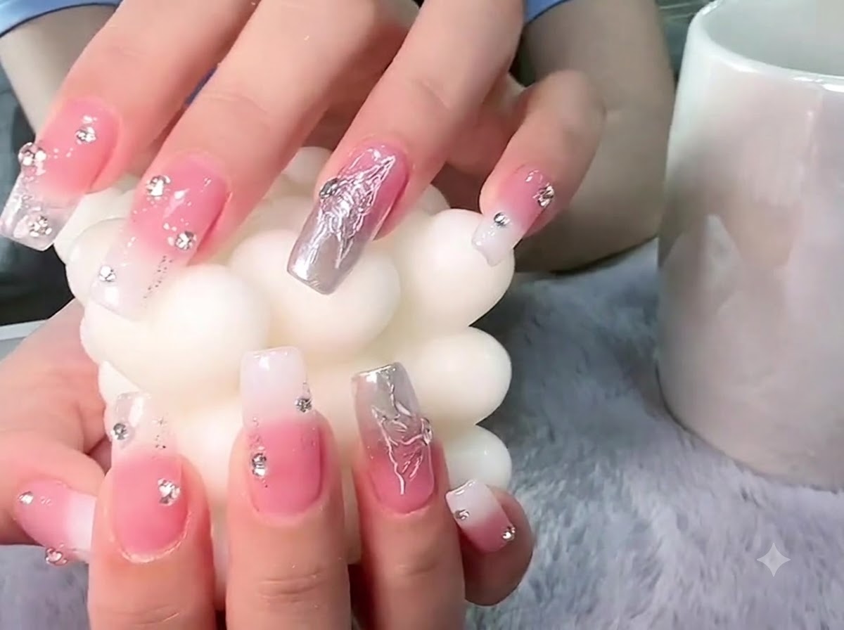 Mani che tengono una candela a pilastro bianca e testurizzata con focus sulla nail art della farfalla 3D argentata.