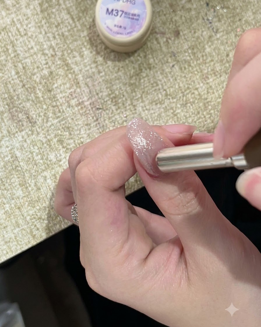 Un magnete cilindrico tenuto vicino alle cuticole di ununghia dipinta e scintillante, che dirige i riflessi magnetici verso lalto.