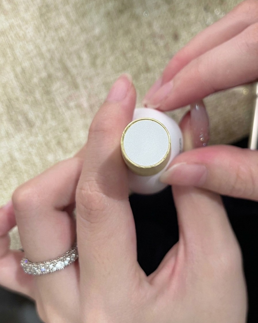 Una boccetta di top coat trasparente tenuta in mano, pronta per sigillare la nail art completata.