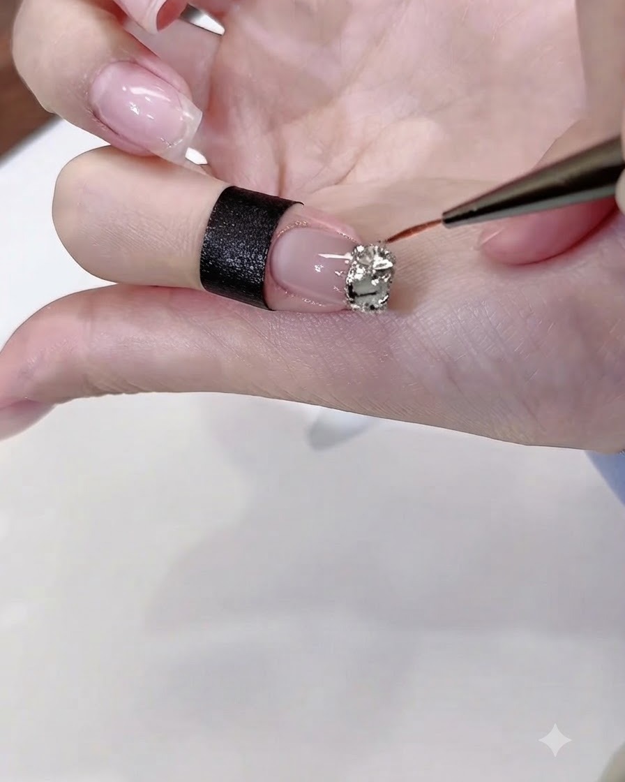 Un sottile pennello per nail art applica con precisione la colla in gel trasparente per diamanti attorno ai bordi di un cluster di strass su ununghia smaltata.