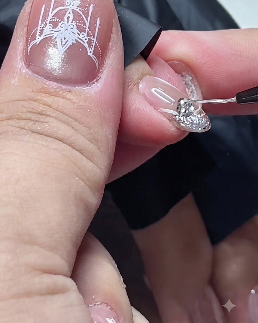 Un pennello di dettaglio fine che applica il top coat attorno alla base di uno strass su ununghia.