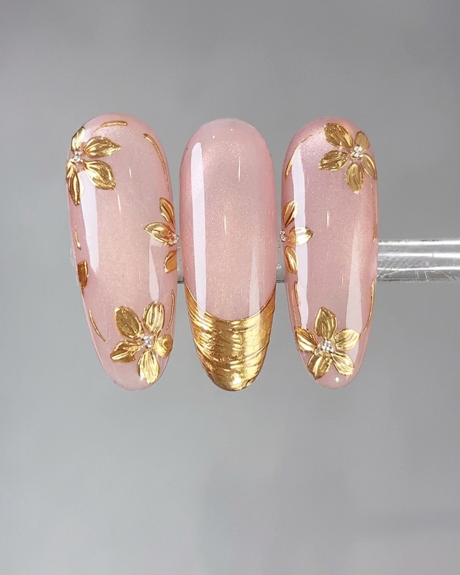 Un applicatore in spugna che preme la polvere a specchio vintage gold su un design dettagliato per unghie.
