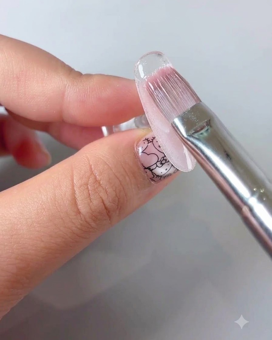 Un pennello per manicure che applica un top coat sigillante trasparente su un design per unghie floreale.