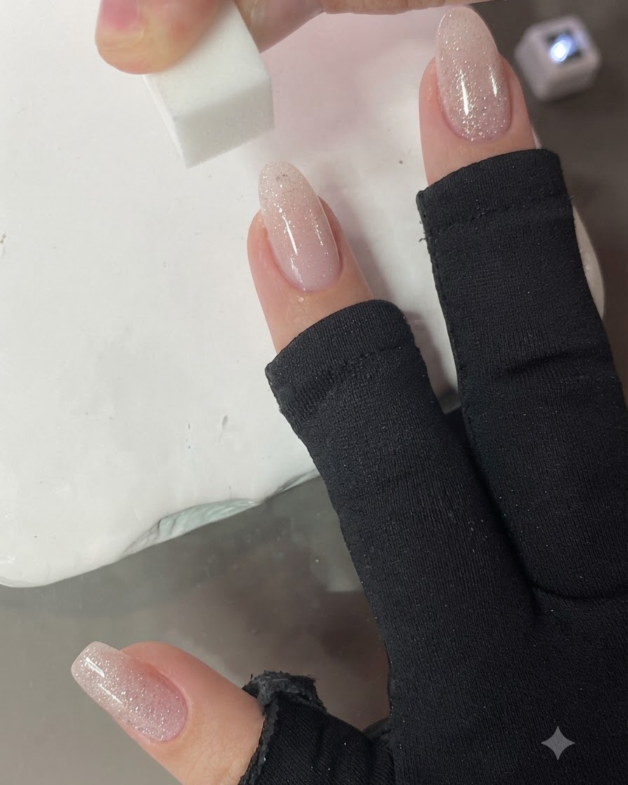 Una piccola spugnetta che tampona verticalmente sullunghia per sfumare il gradiente rosa nude.