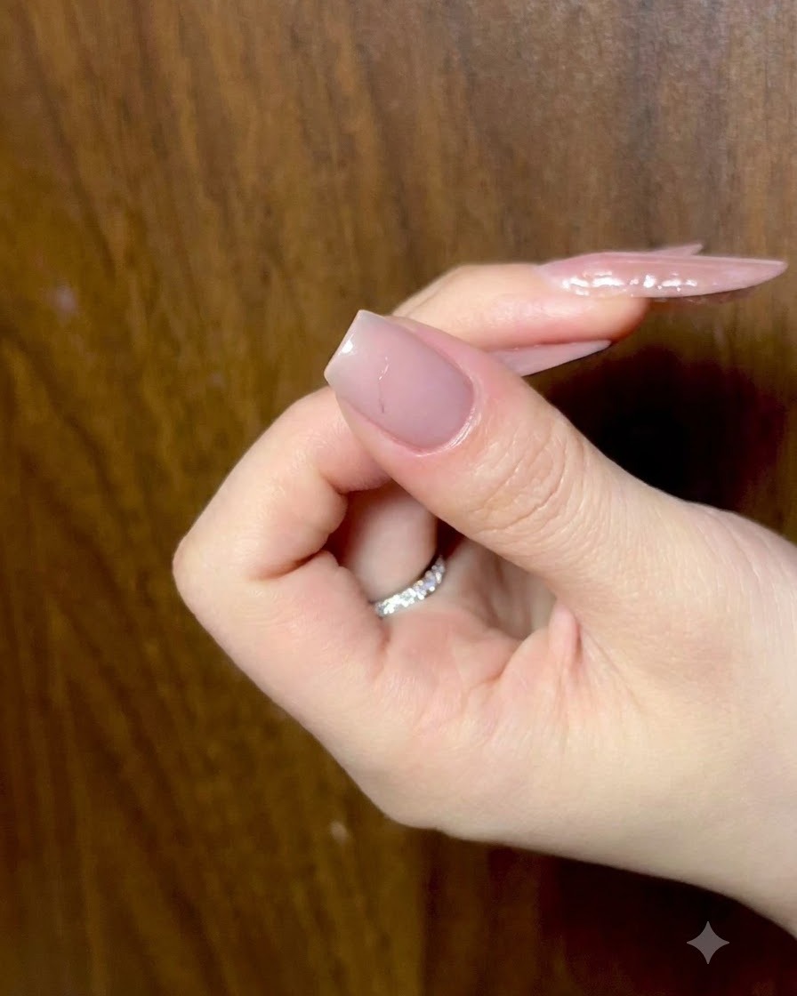 Una mano a riposo con le dita leggermente arricciate, che mostra unghie nude preparate sotto una luce ambientale.
