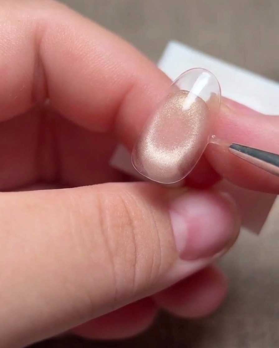 Una mano che utilizza un pennello liner sottile per rifinire i bordi della linea del sorriso su una punta dunghia.