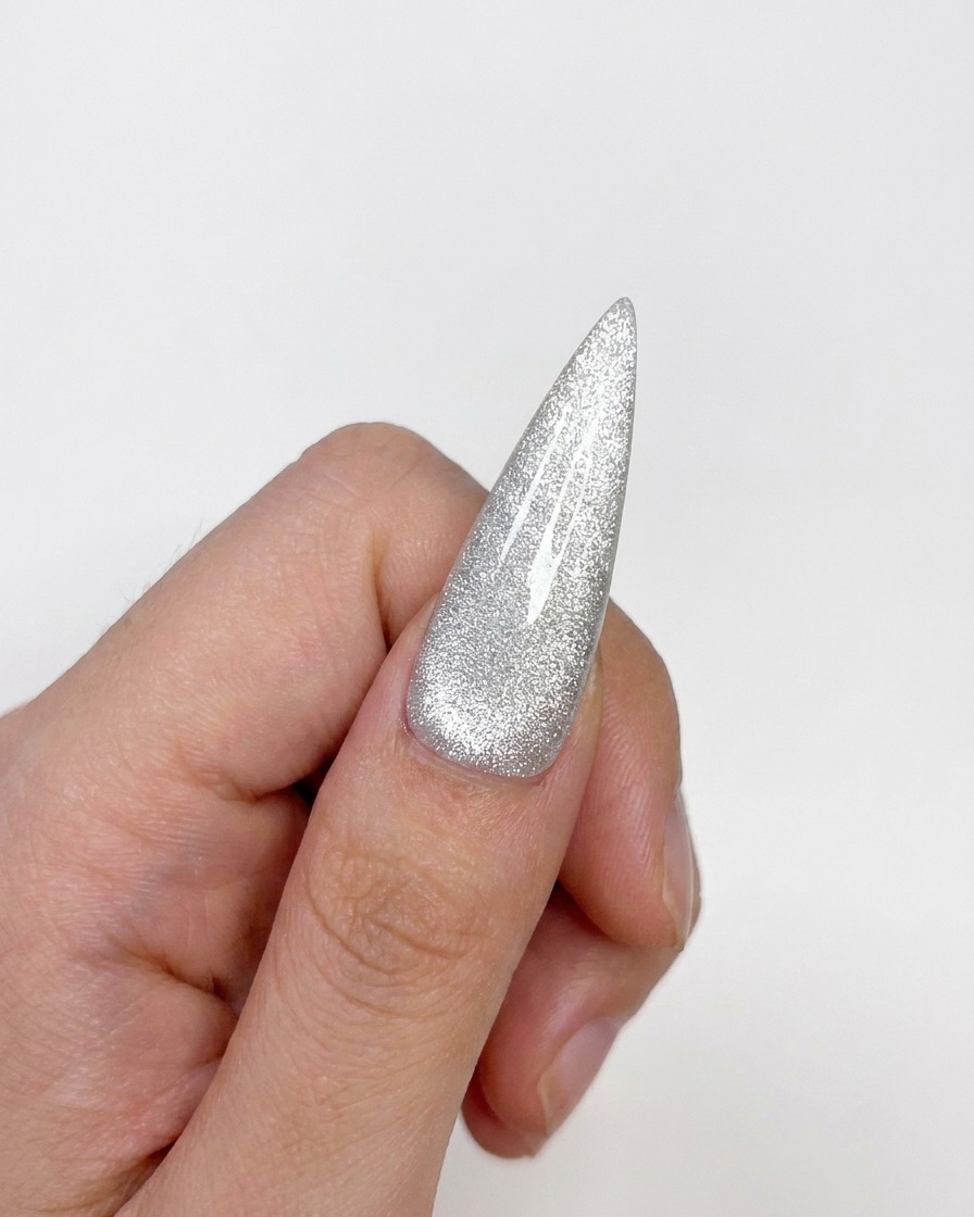 Una tip unghia cat-eye completata che mostra una finitura lucida e polimerizzata con un punto luce centrato.
