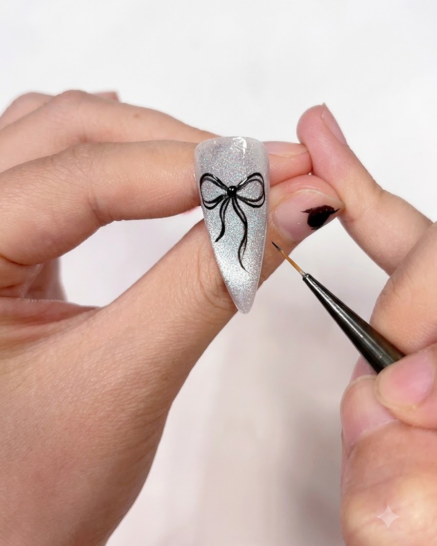 Uno scatto in primo piano che mostra un pennello liner fine che ripassa i contorni del fiocco nero per renderli nitidi, opachi e uniformi.