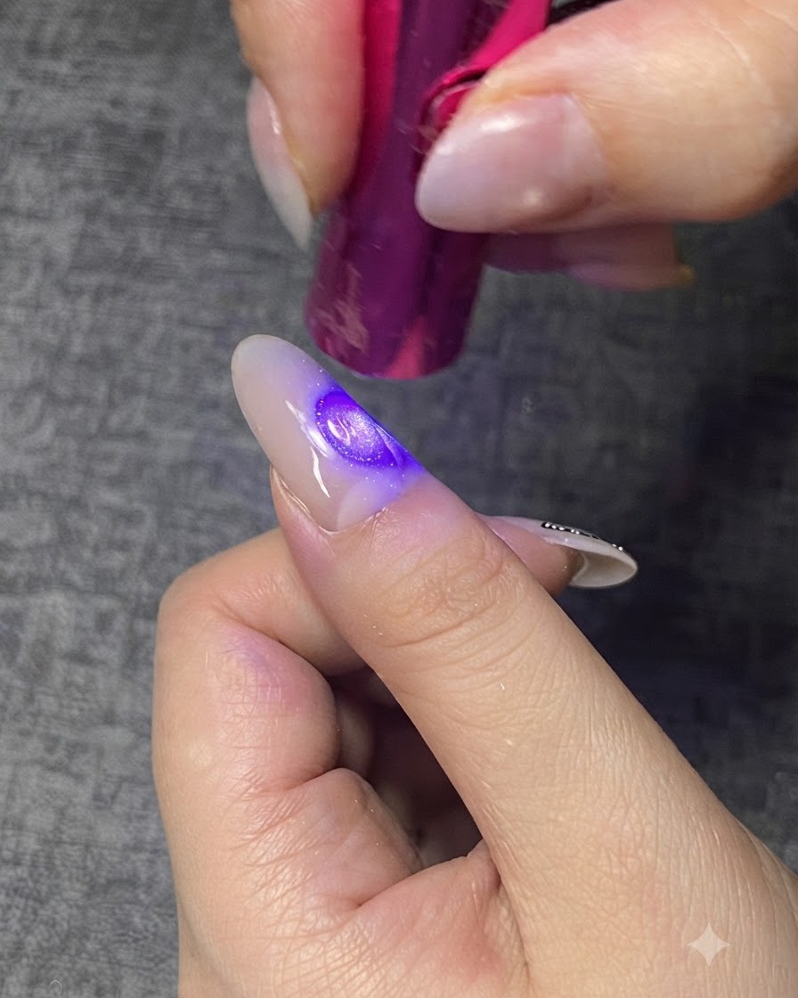 Una mini lampada UV/LED viola polimerizza uno strato di gel trasparente su ununghia.