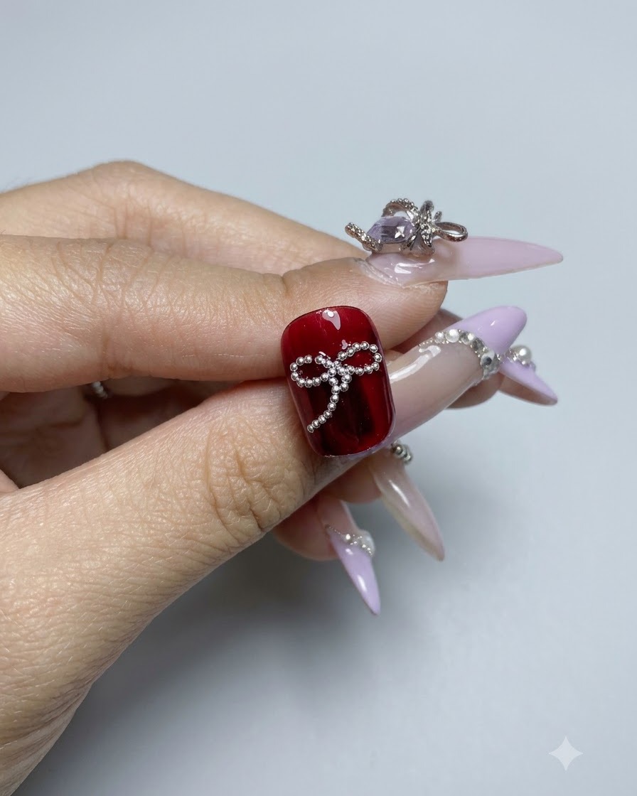 Un design completo di fiocco di perline su una superficie di unghia in gel rosso scuro lucido visto da vicino.