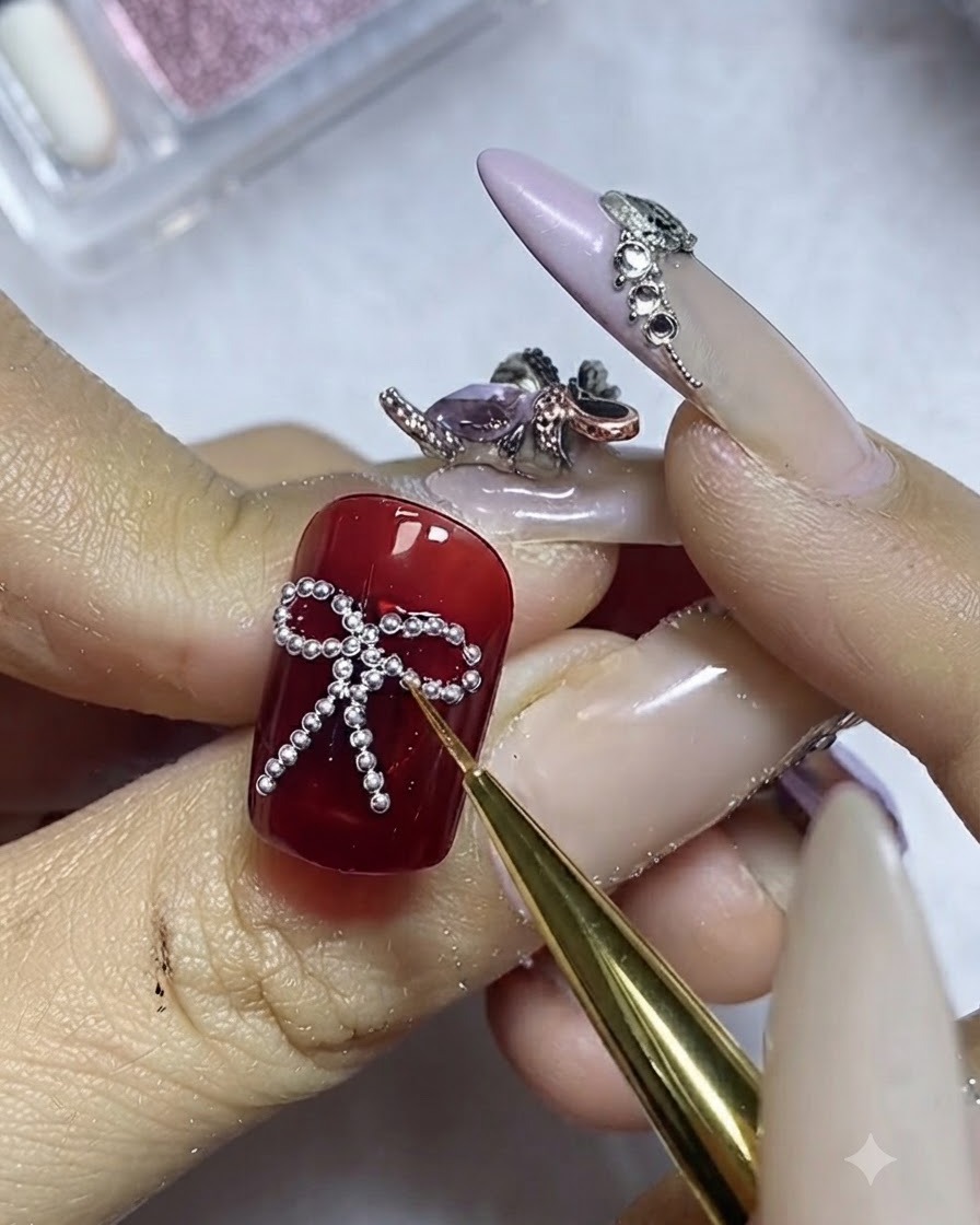 Un pennello fine che applica con cura il top coat attorno al perimetro delle sfere dacciaio argentate su ununghia rossa.