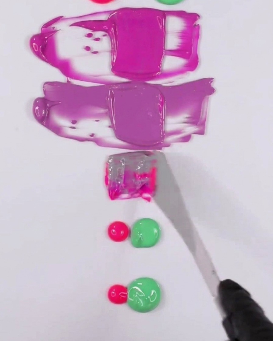 Una spatola di metallo che unisce una miscela di smalto gel rosa e verde per creare una tonalità viola smorzata.