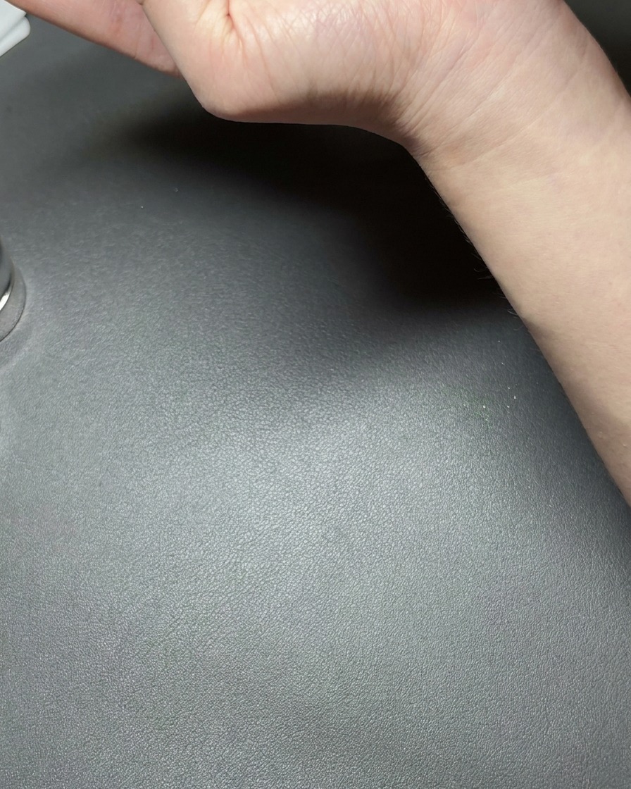 Una mano che tiene un piccolo magnete al neodimio vicino a ununghia rivestita di gel cat-eye verde metallizzato, creando una linea riflessa luminosa.