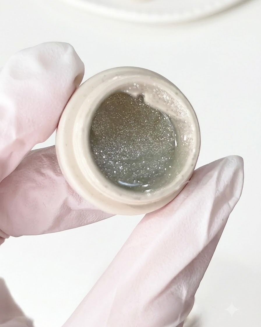 Un pennello applica il gel con diamante frantumato su una base per unghie preparata.