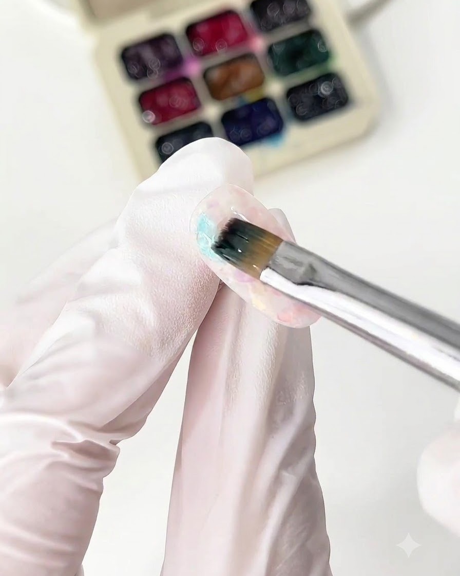 Un pennello sottile applica il glass gel blu sulla punta di ununghia.