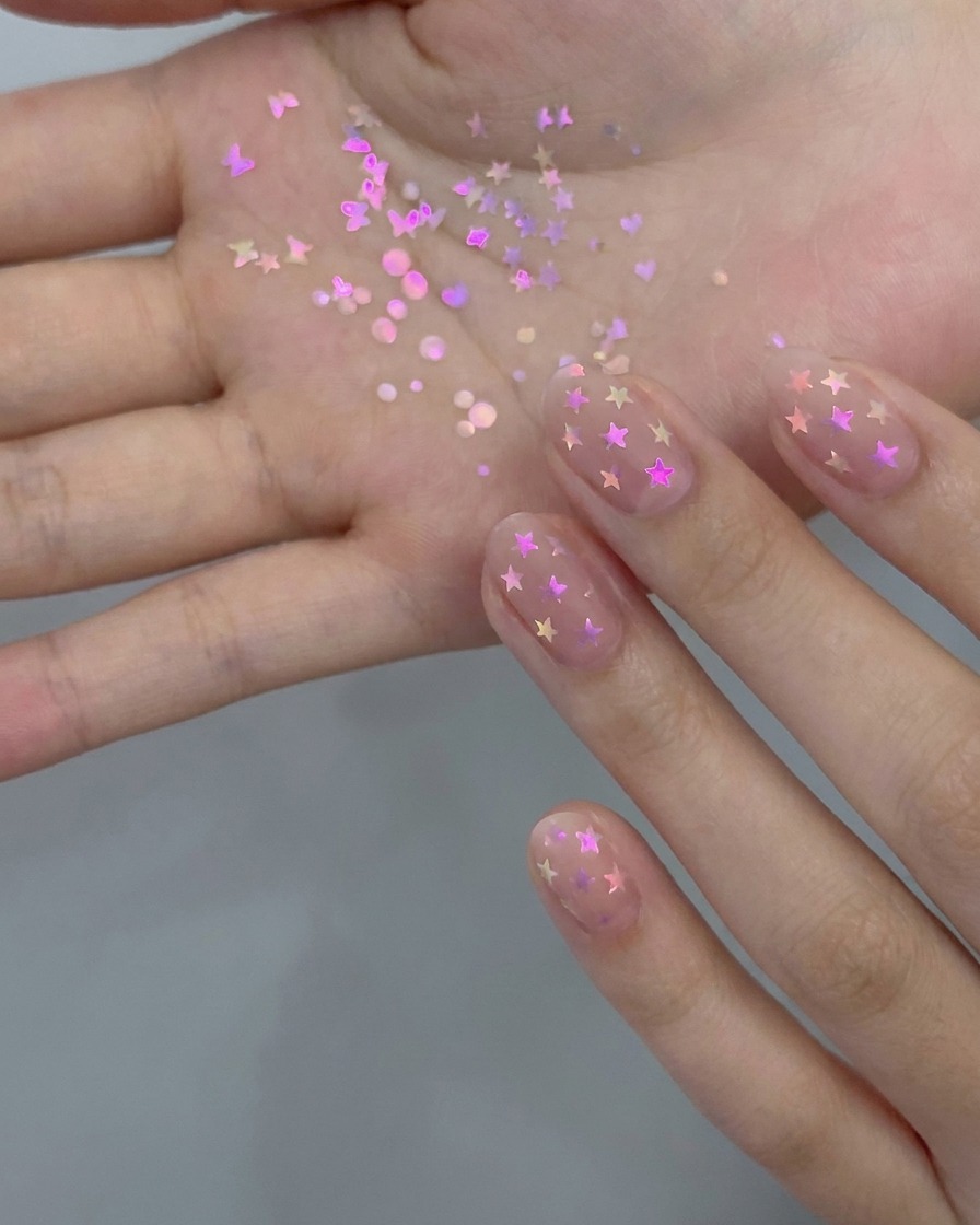 Un pennello da manicure che applica un sottile strato di smalto gel nude trasparente su ununghia naturale.